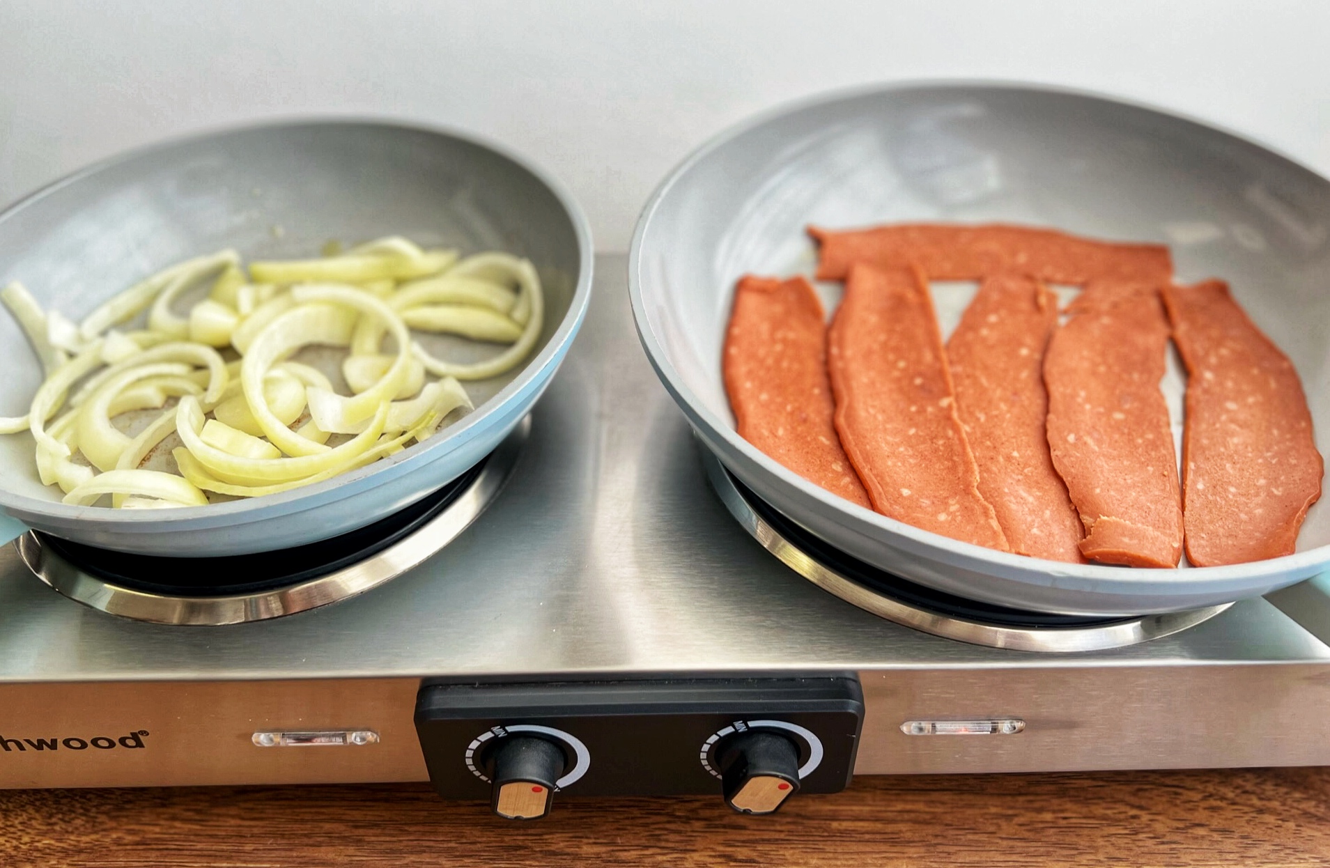 Onions and vegan bacon cooking in skillets